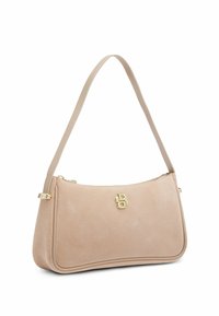 Sac à épaule en daim beige avec emblème logo doré et fermeture éclair, doté d'une seule bandoulière pour un port à la main ou à l'épaule.