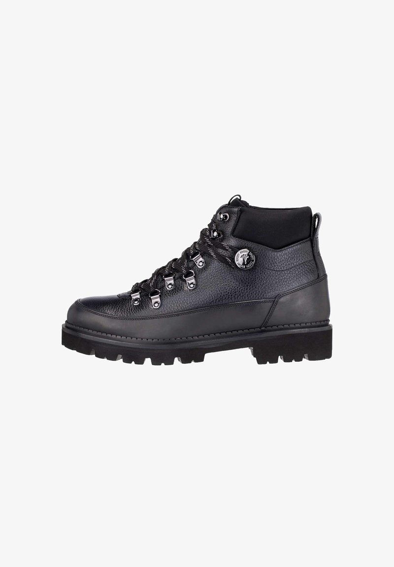 Botte de randonnée en cuir noir avec œillets métalliques, semelle à crampons épaisse, col rembourré et écusson rond avec logo sur la cheville.
