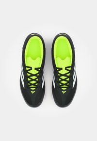 Scarpe sportive nere con strisce bianche, dotate di un interno e lacci di un vivace verde neon. Progettate con una superficie testurizzata e un profilo basso.
