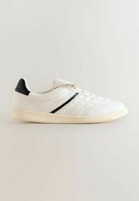 White leather sneaker with black accents and textured heel. Features five eyelets, a side stripe, and a textured rubber sole.