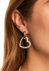 Pendientes de aro de oro con un diseño en forma de corazón, caracterizados por un contorno de cristal y un enganche dorado liso.