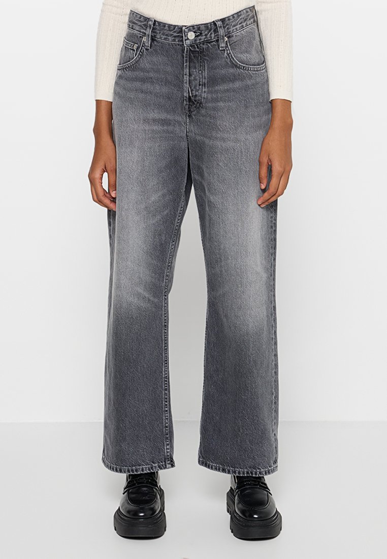 Höga, vida jeans i blekgrå denim. Har framfickor, bälteshällor och knappgylf, kombinerat med svarta platåskor.