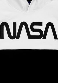 T-shirt con la parte superiore bianca e la parte inferiore nera; presenta un grande logo nero "NASA" sul petto, realizzato in materiale cotone.