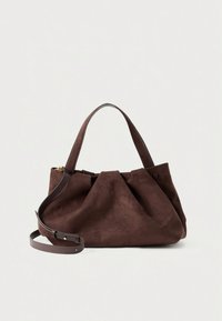 Brun ruskindshåndtaske med plisseret design, der har to korte håndtag og en aftagelig skulderrem i læder. Indeholder en lukning med trykknap.