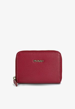 Cartera de cuero roja con superficie texturizada, cierre de cremallera y acentos en tono dorado del logo. Forma rectangular compacta con esquinas redondeadas.