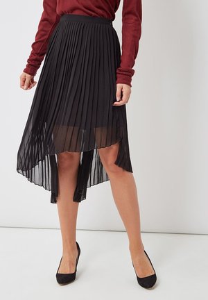 Falda midi negra plisada con bajo desigual, tejido transparente para efecto de capas y cinturilla sólida. Se lleva con tacones negros.