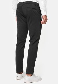 Mørkegrå bukser med slim passform og glat tekstur. Har to baglommer, en knap og et elegant design. Bæres med hvide sko.