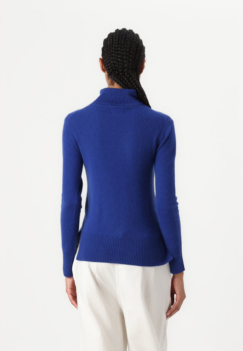 Pull à col roulé bleu en maille douce, avec un ourlet et des poignets côtelés, une coupe décontractée et sans motifs visibles.