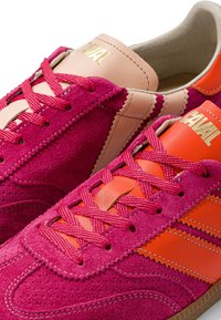 Paire de baskets en daim avec des panneaux roses et orange, des lacets roses et le marquage doré « CAVAL » sur la languette.