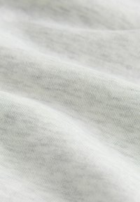 Világosszürke szövet lágy, sima textúrával. Finom mintázatú, enyhén színátmenetes mintával, finom kötött részletekkel és enyhe fényességgel.