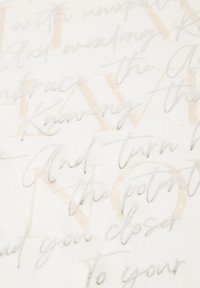 Bílá látka se strukturovaným stříbrným a béžovým textem v různých písech, vytvářející vrstvený efekt s frázemi a vizuálním zájmem.