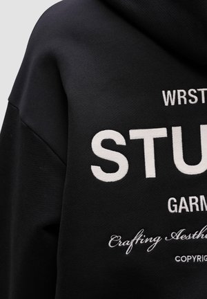 Black hoodie made of cotton blend fabric, featuring white embroidery with text "STUDENT" and additional design elements on the front.