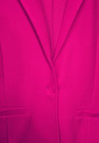 Fuksjowa marynarka z klapą z wcięciem, zapinana na jeden guzik, z dwoma przednimi kieszeniami i prążkowaną fakturą.