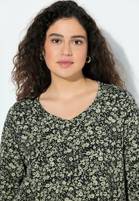 Schwarze Bluse mit floralen Mustern, V-Ausschnitt, zarten grünen Blumenmustern, leichtem Stoff und lockerer Passform.