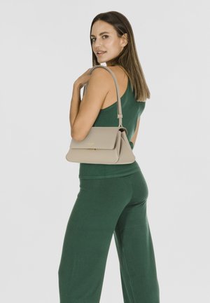 Beige handbag with a gold hardware accent, rectangular shape, and a flap closure, carried on one shoulder against a white background.