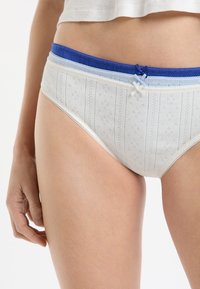 Mutandine di cotone bianco con elastico in vita azzurro chiaro e blu. Presentano un motivo strutturato con dettagli ricamati e un piccolo fiocco.