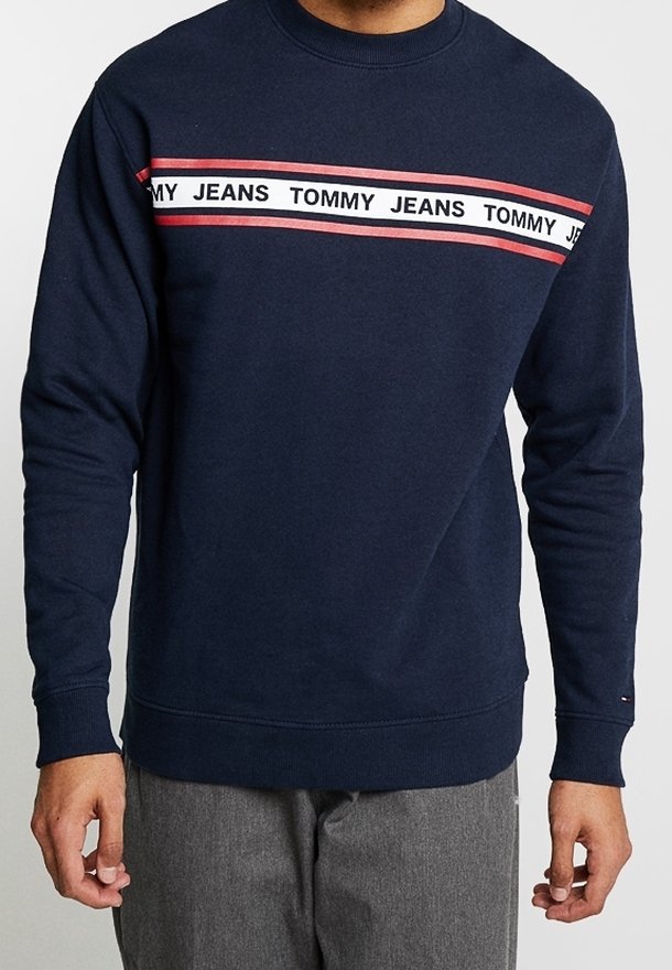 Sweat-shirt bleu marine en coton, avec un col rond et des manches longues. Comprend une bande horizontale avec un logo en rouge et blanc.