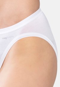 Primo piano di una persona che indossa una mutanda bianca a vita alta con il marchio "mey LIGHTS" sul lato dell'elastico.