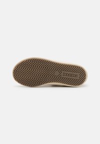 Suola della sneaker Geox con una base in gomma beige, caratterizzata da un motivo a zigzag per una migliore aderenza. Include il logo al centro.