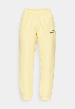 Gelbe Jogginghose aus glattem Material mit elastischem Bund, ausgestattet mit einem kleinen schwarzen Logo am linken Bein und Reißverschlussöffnungen an den Knöcheln.