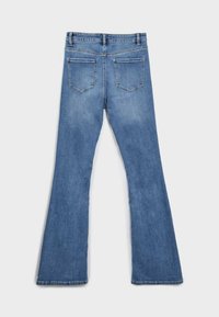 Světle modré džíny s rozšířenými nohavicemi, klasickou denimovou texturou, pěti kapsami a zapínáním na zip. Na zadní straně jsou dvě nášivkové kapsy a minimální vyblednutí.