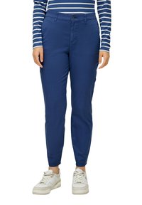 Blaue Baumwollhosen mit Slim-Fit, ausgestattet mit einem Knopfverschluss und Seitentaschen, kombiniert mit weißen Sneakers und einem gestreiften Langarmshirt.