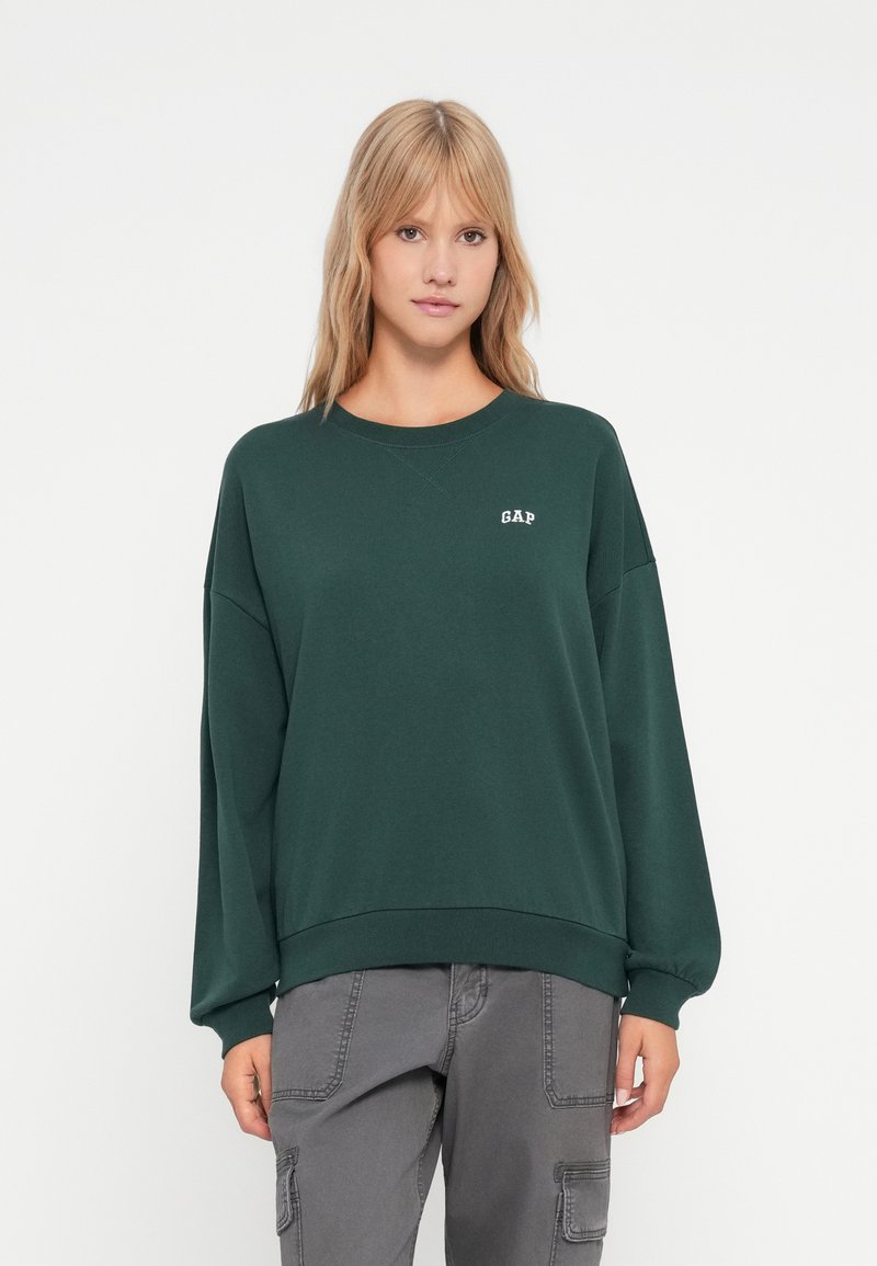 Felpa verde in cotone con scollo tondo, spalle basse, orlo a costine e logo "GAP" bianco sul petto. Vestibilità comoda.