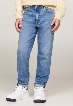 Jeans in denim azzurro chiaro con vestibilità dritta, dotati di tasche, chiusura con bottone e orli arrotolati, abbinati a sneakers bianche.