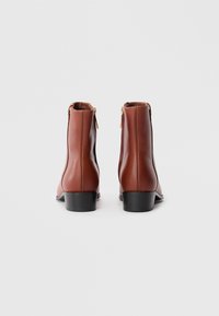 Brune lær ankle boots med en glat overflade, lynlås lukning bagpå og en lav sort hæl. Simpelt design, uden synlige mønstre.
