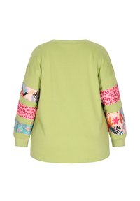 Felpa oversize verde con maniche decorate da stampe floreali e animali in tonalità di rosa, blu e giallo.