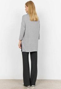 Gray long-sleeve tunic with side slits paired with dark gray pinstriped wide-leg pants and silver block-heeled shoes. Smooth texture.