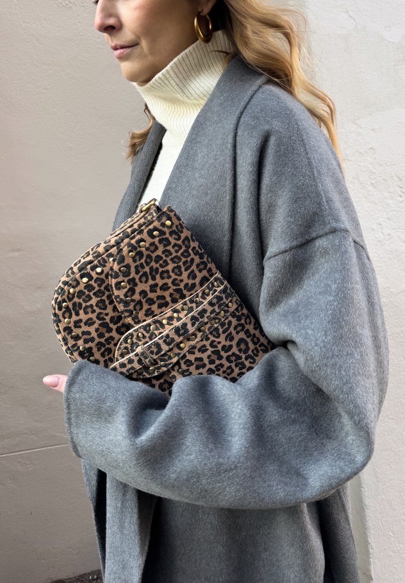 Leopard print clutch with gold studs, resting against a gray wool coat. Features a zipper and a curvy shape, complemented by a soft texture.