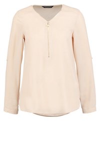 Blusa beige chiaro realizzata in tessuto liscio, con scollatura a V, dettaglio con zip frontale e maniche lunghe con polsini abbottonati.