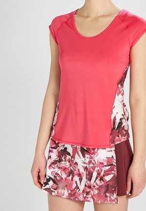 T-shirt de sport à manches courtes et col rond en rose vif, associé à une jupe à motif floral avec un panneau bordeaux sur un côté.