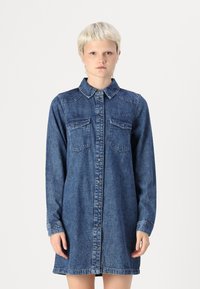 Denim skjortklänning med knappstängning, spetsig krage, långa ärmar och två bröstfickor. I en medelblå tvätt med en klassisk passform.
