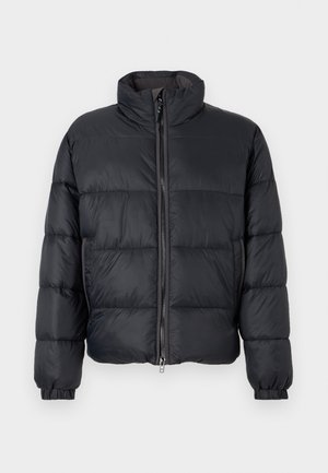 Μαύρο μπουφάν πούφ με ψηλό γιακά, οριζόντια ραφή, μπροστινό φερμουάρ και ελαστικούς καρπούς. Φτιαγμένο από ελαφρύ, λεία υλικό.