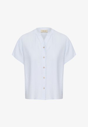 Camicia azzurra chiara con maniche corte, caratterizzata da un colletto bordato in pizzo e bottoni in legno sulla parte anteriore. Tessuto dalla texture particolare.