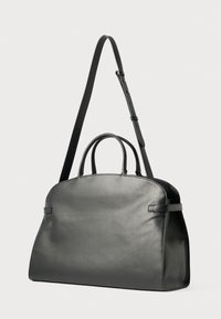 Borsa tote in pelle nera con due manici superiori e tracolla rimovibile. Silhouette arrotondata con texture liscia e dettagli hardware minimi.