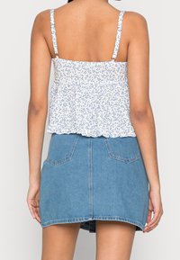 Vit blommönstrad topp med volangkant, i kombination med en ljusblå denimkjol med två bakfickor och en svag A-linjeform.