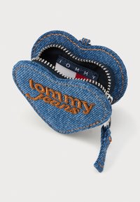 Farmernadrág szív alakú tok narancssárga varrással és "tommy jeans" hímzéssel. Ezüst színű cipzáras záródás és textil bélés belső logócímkével.