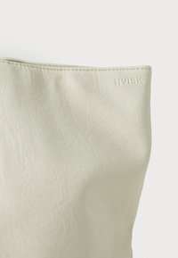 Sac HVISK beige clair, fabriqué en matériau texturé, avec une finition lisse et un logo en relief sur le côté. Design simple et moderne.