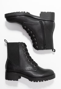 Bottines en cuir noir avec un bout arrondi, fermeture à lacets à l'avant, fermeture éclair latérale, panneau élastique et semelle en caoutchouc texturée.