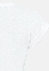 T-shirt blanc à manches courtes avec un tissu doux et légèrement texturé. Encolure arrondie et détails des poignets retournés pour un look décontracté.