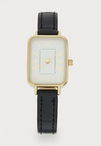 Reloj rectangular dorado con esfera blanca, marcas en números romanos y una correa de cuero negro con detalles de costura.