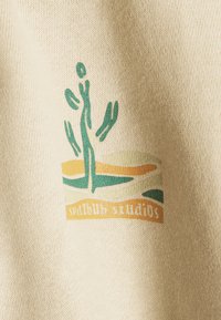 Cremfarbenes Gewebe mit glatter Textur, das ein grünes und oranges grafisches Logo einer Figur und einer abstrakten Landschaft zeigt.