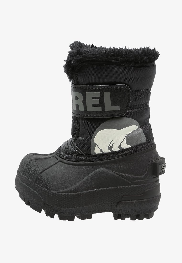 Botte d'hiver isolée noire avec semelle épaisse, doublure en fausse fourrure, sangle Velcro étiquetée "SOREL" et illustration d'ours polaire sur le côté.