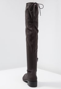 Botas de ante gris oscuro hasta la rodilla, con punta redonda, cierre de cremallera lateral y lazo ajustable en la parte superior. Tacón plano y apilado.