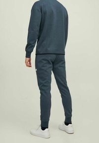 Mörkgrå sweatshirt och matchande joggers i mjukt material, med ribbat fåll och manschetter, kombinerat med vita sneakers.