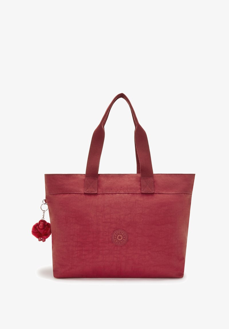 Red tote bag made of textured material with two handles, featuring a round logo and a pom-pom charm attached.