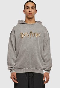 Grå oversize hoodie lavet af blødt stof, med et stort guld "Harry Potter" logo på forsiden, samt en front kangaroo lomme.